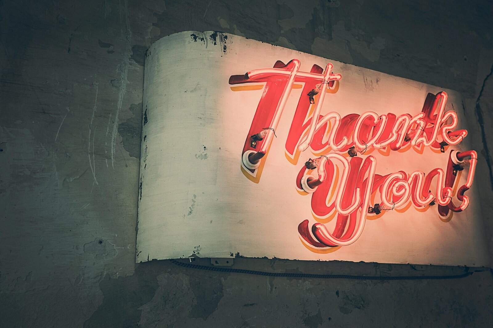 Retro neon 'Thank You' sign glowing warmly against a rustic wall, creating a nostalgic ambiance.